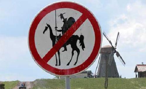No Tilting at Windmills Sign appearing in front of an old style Dutch windmill